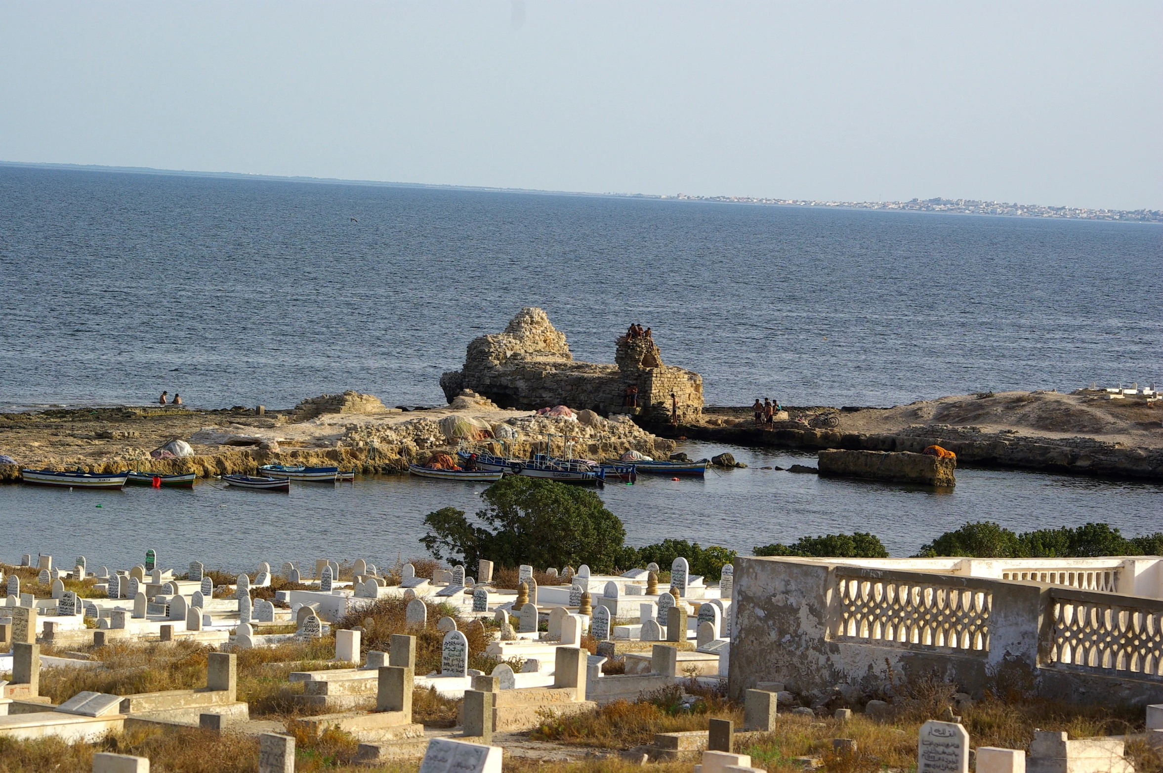 small cemetery with small graves by water with boats nearby