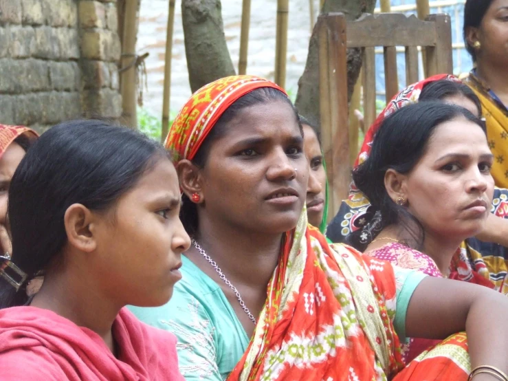 several women sit outside with one staring at the camera