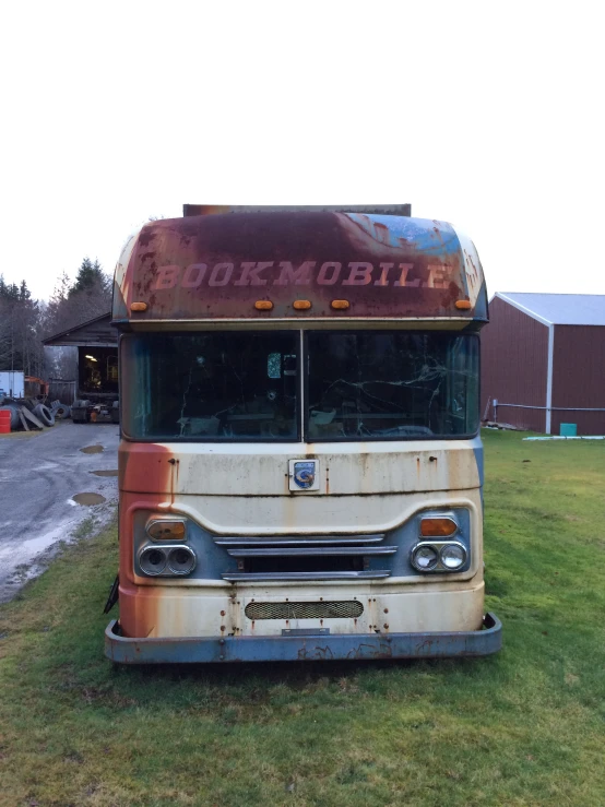 an old rusty bus sitting on top of green grass