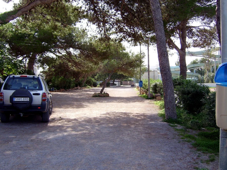 a white car parked near trees and parking meter