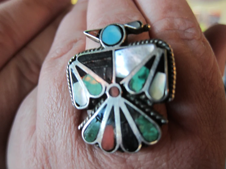 a close up of someone holding a ring with colored stones