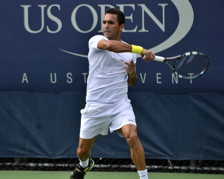 a tennis player swinging a racket in front of a us open sign