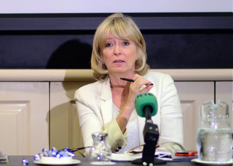 a woman sitting in front of a microphone while holding a pen in her right hand