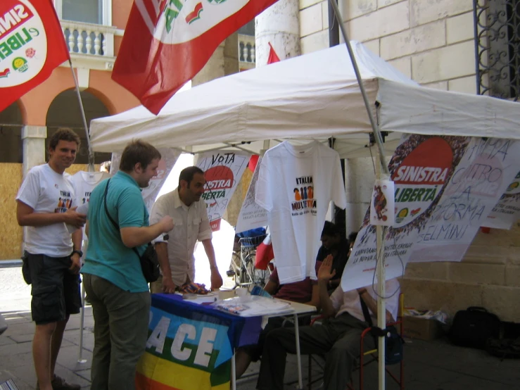 some men are selling shirts from some vendor's tent