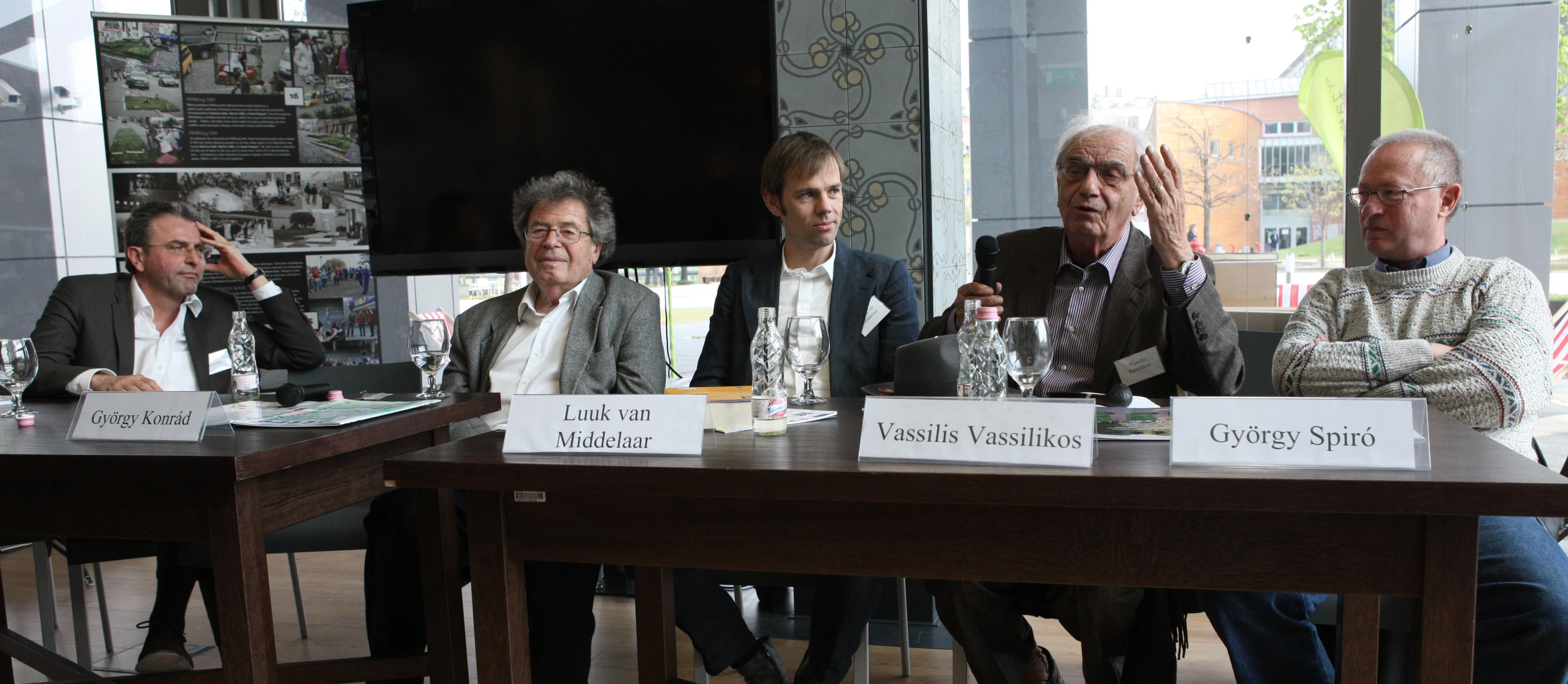 four men sit behind a table during an event