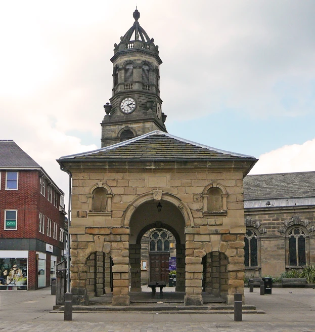 a clock tower sits in the middle of an empty square