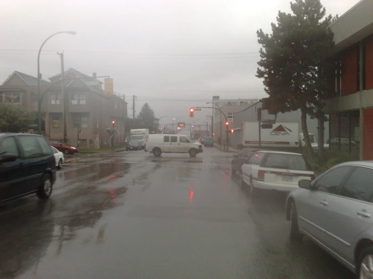 a wet street filled with cars driving through rain