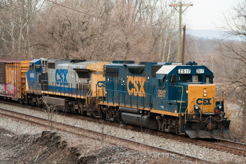 two train cars sit on a track as a power lines hangs overhead