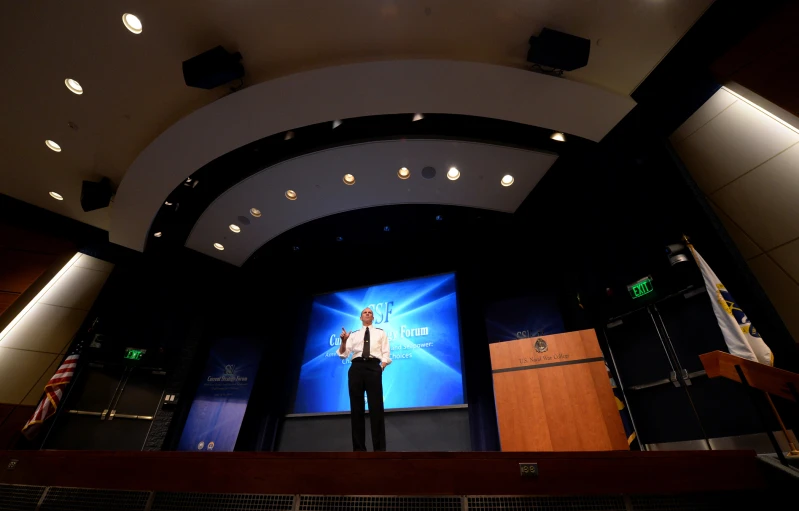 a man stands on a stage speaking on the phone