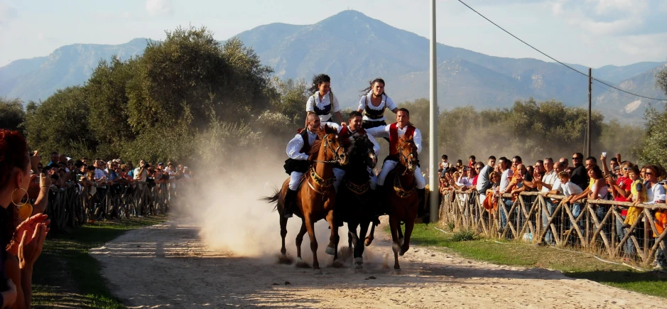 three people riding horses during a competition while spectators watch