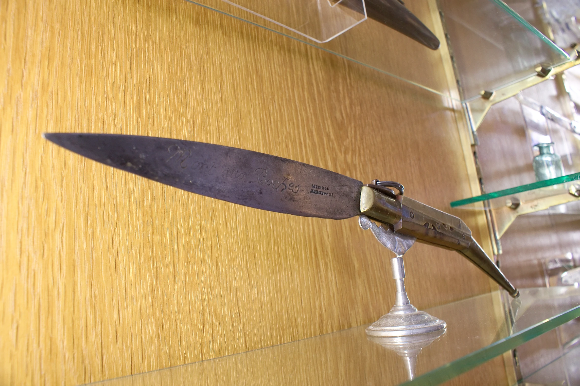 a knife hanging on a wooden table near a glass shelf