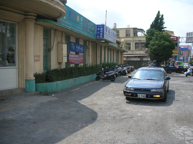 a car is parked on the street in front of a row of buildings