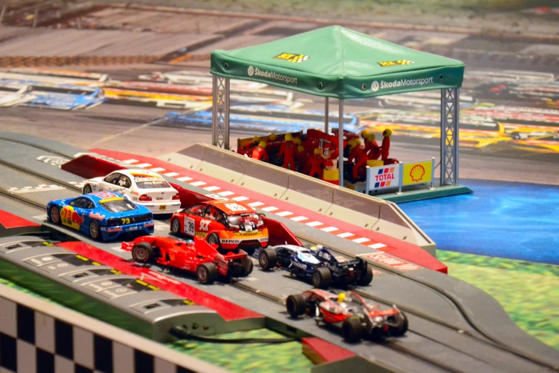 a model race track with toy cars being pulled by two men in drag suits