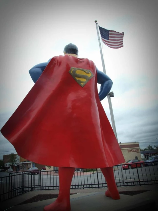 a statue of superman stands near an american flag