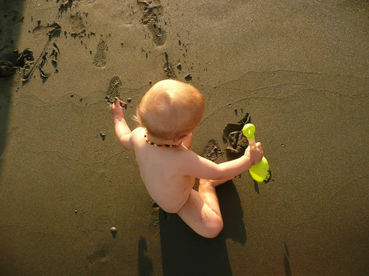 a baby plays with his toy at the beach