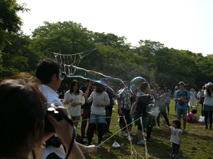 group of people standing on top of a field with bubbles