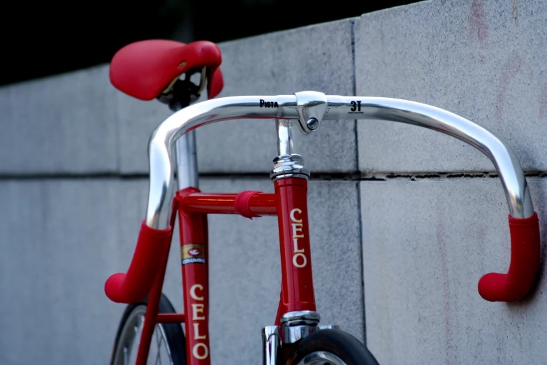 the red bicycle is leaning against a gray building