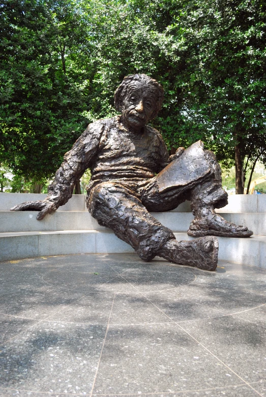 a sculpture of a person with a book on the cement