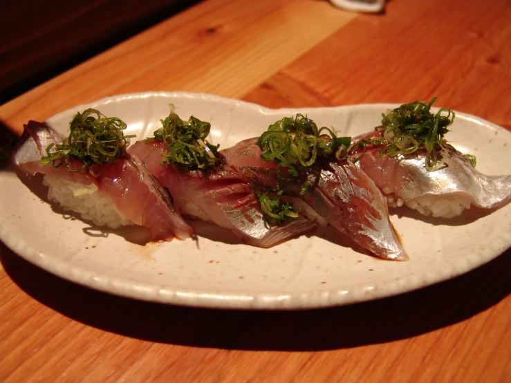 three sushi rolls on a white plate on top of a wooden table