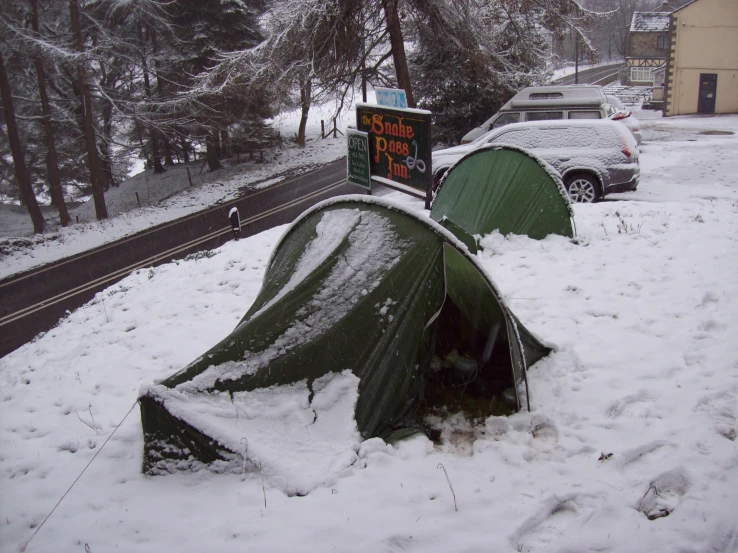 tents covered in snow near a parking lot and trees