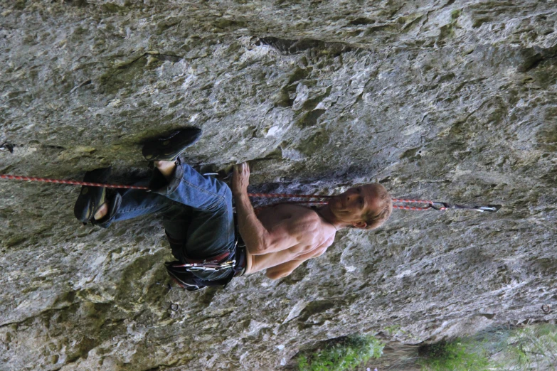 a shirtless man on a mountain climbing up