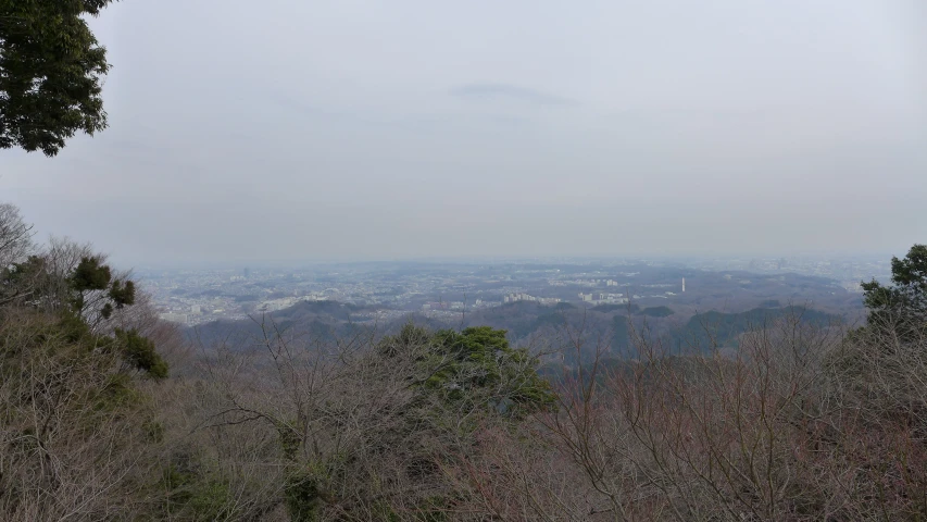 the view from the top of a mountain with some hills and buildings in the distance