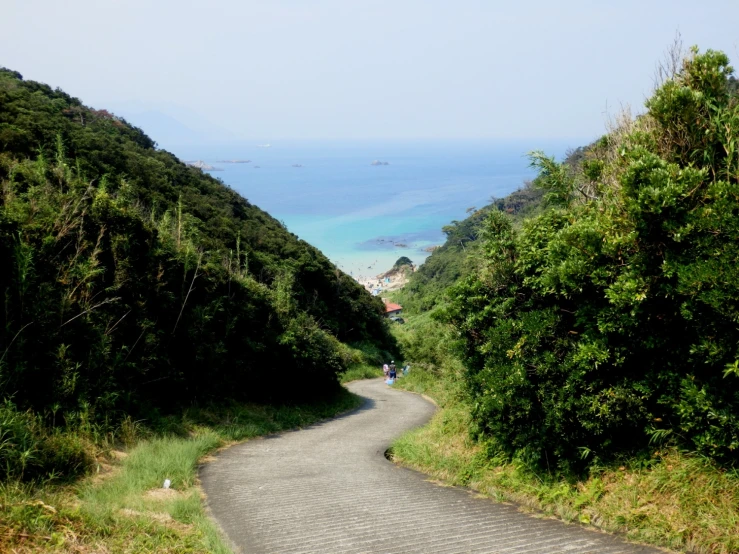 a view of a wide, narrow country road with a blue ocean behind