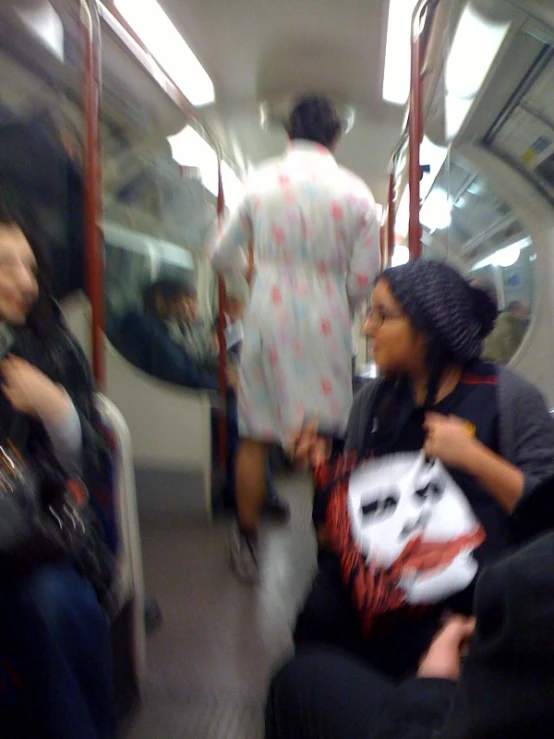 two people sitting on the subway with luggage on their back