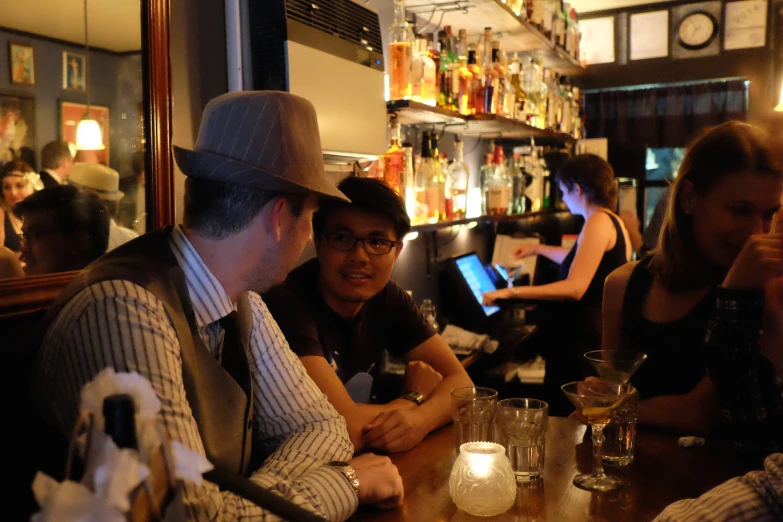 men and women sitting at a table in a restaurant, with a laptop on it