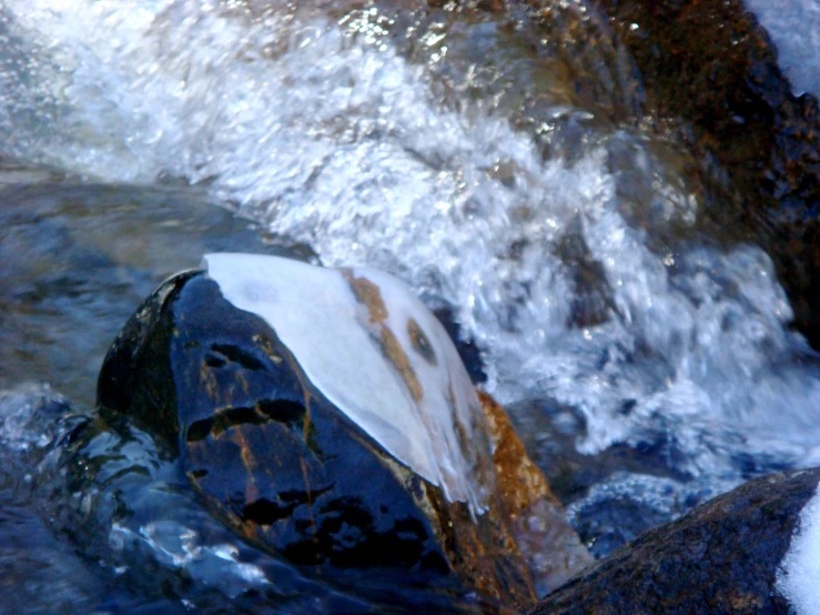 a large rock in the middle of a rushing river