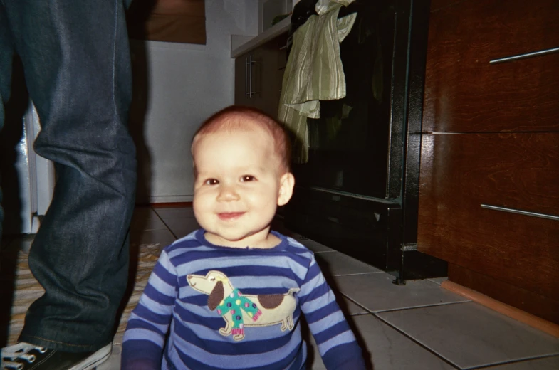 a smiling toddler in striped pajamas next to a person