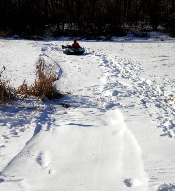 a person riding a snow mobile down a snowy path