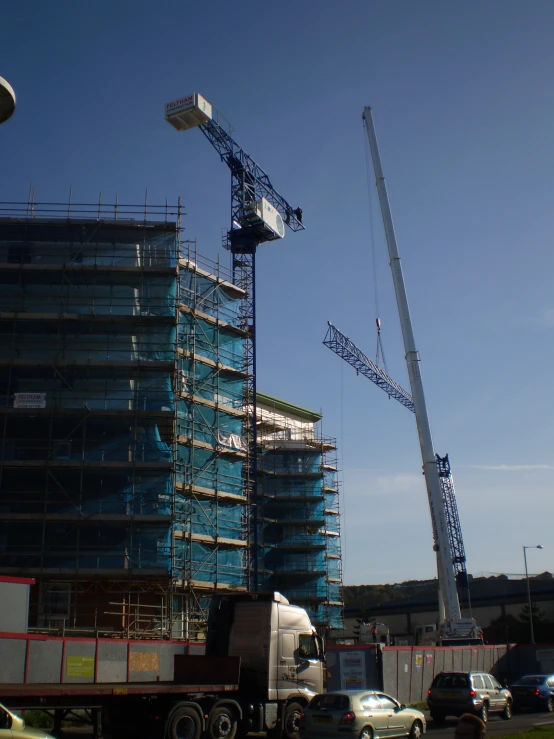 a crane next to a building with cars passing by