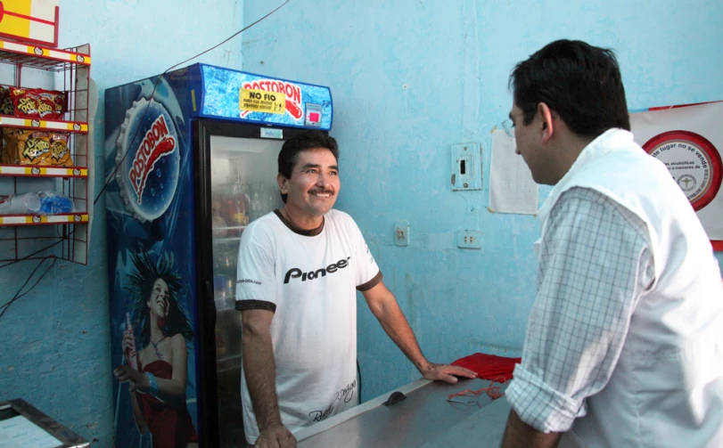 two men in white shirts are talking and smiling