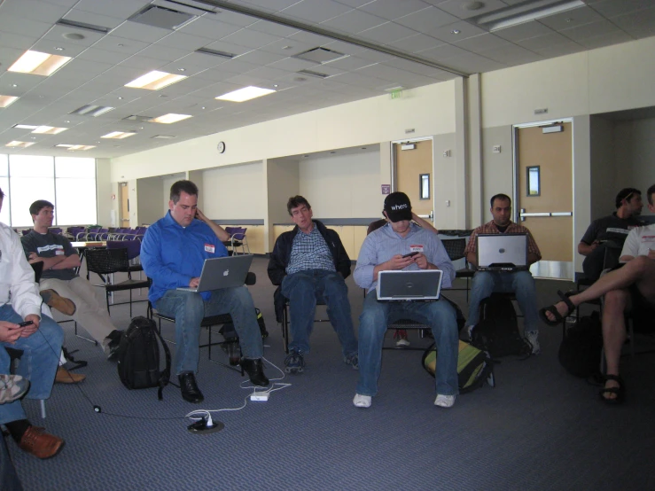 a bunch of guys are sitting with laptops