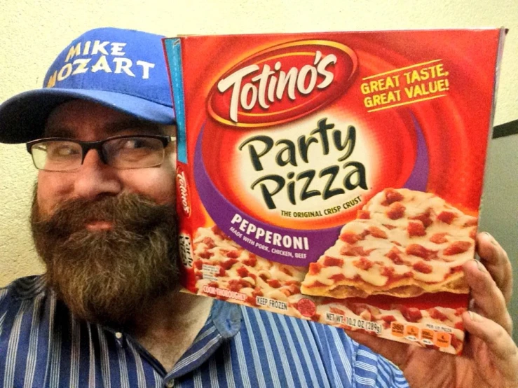 the man is holding up a pizza that's for his birthday