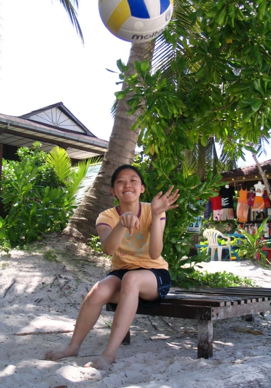 a girl in a yellow shirt tossing a volleyball