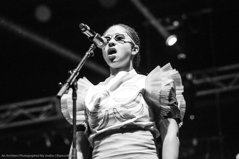 a woman in a white top sings into microphones