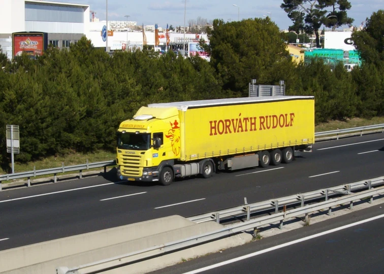 a yellow truck is on the street and near some bushes