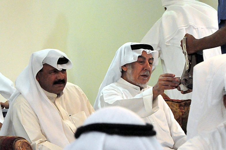 a group of men dressed in white sitting next to each other