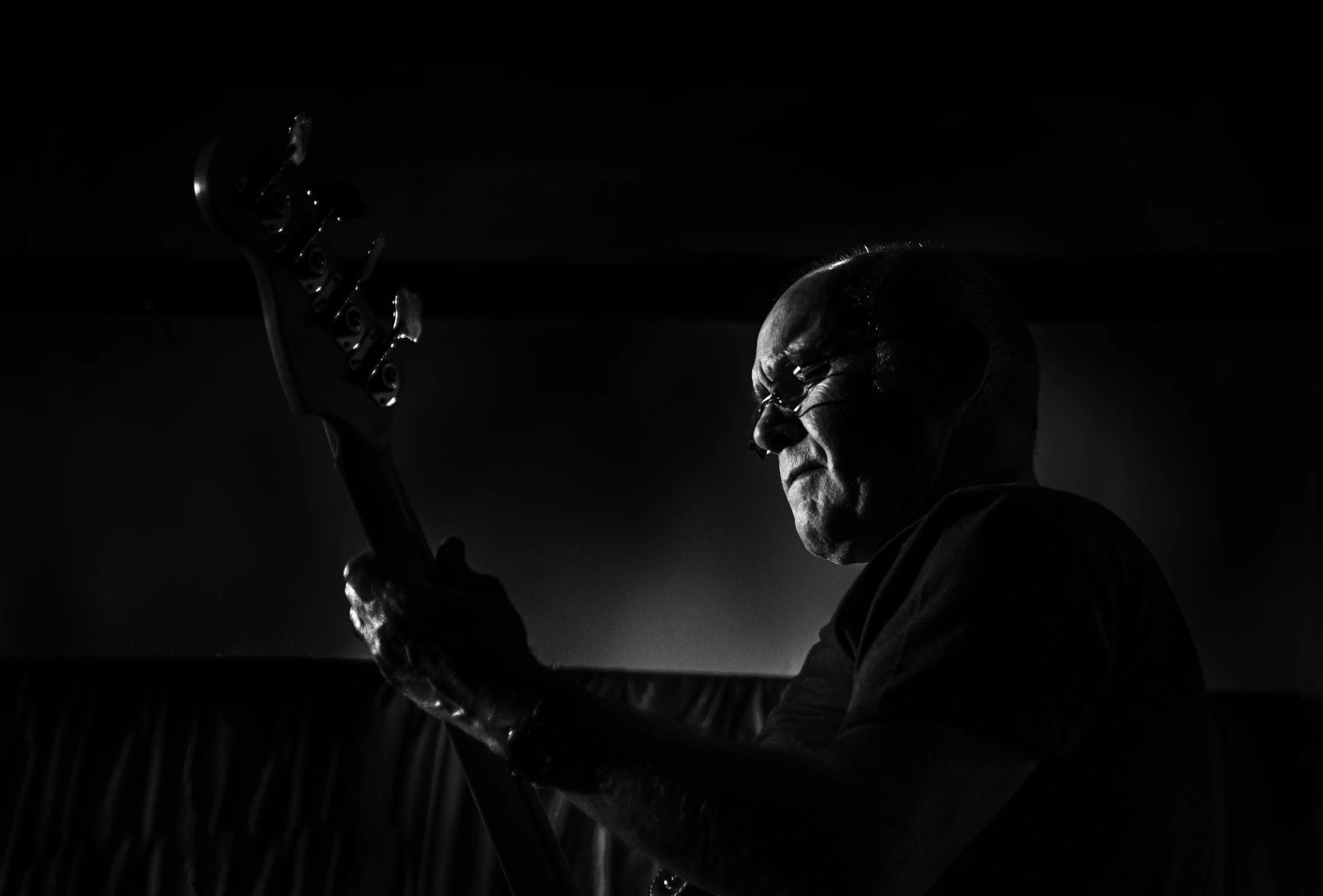 an old man plays his electric guitar in a dark room