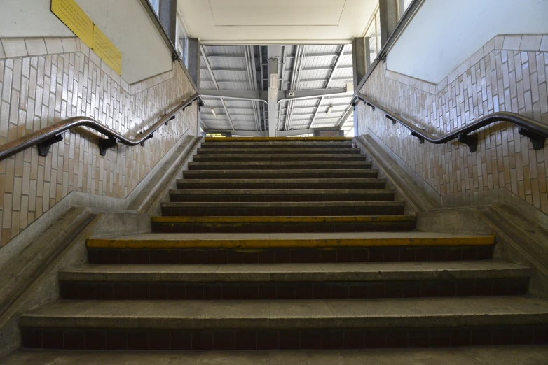 concrete stairway with wooden handrails and tiled walls