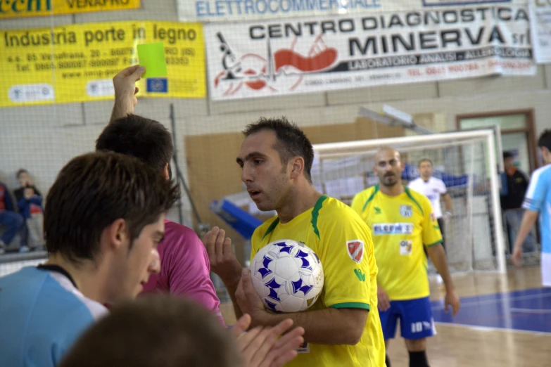 men and women standing around a ball inside of a room