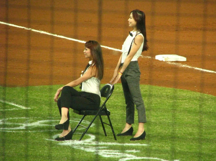 two women sitting in chairs on the field