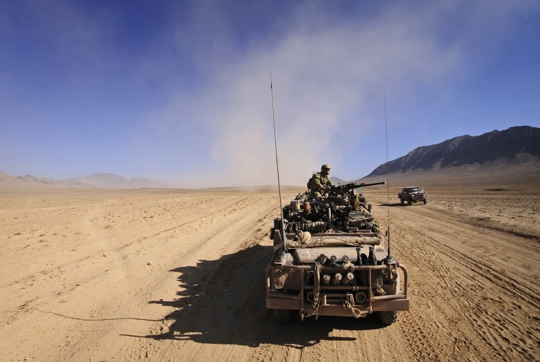 a military vehicle driving down the road in the desert