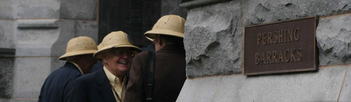 three people with hats are standing by a wall