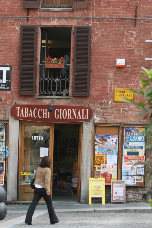 a woman walking past a shop with lots of advertits