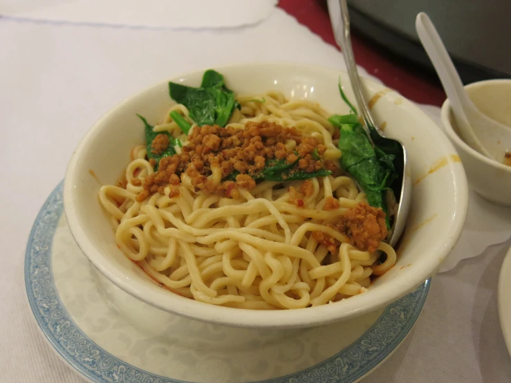 a dish with noodles and meat in a bowl with a spoon