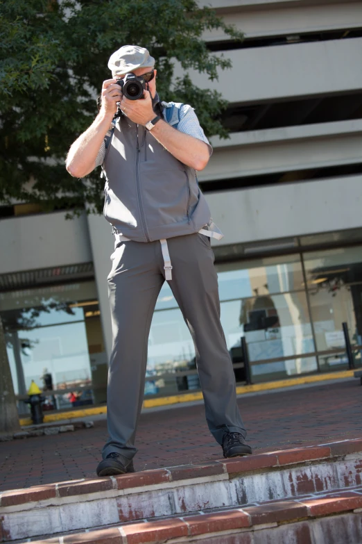 a man in grey clothes takes a picture with his camera