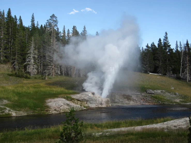 the water is steam rising from the ground next to the fire